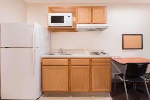 a kitchen with a refrigerator and a sink and a table at WoodSpring Suites Columbus Fort Moore in Columbus