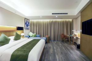 una camera d'albergo con un grande letto e una scrivania di Quality Hotel Zhangye a Zhangye