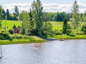 a house on the shore of a lake with a boat at Holiday Home Peukaloinen by Interhome in Hirsjärvi