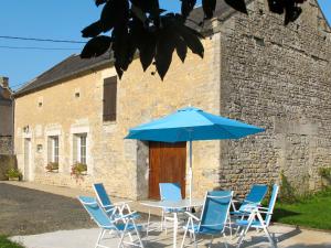a table with chairs and an umbrella in front of a building at Holiday Home Le Clos Renard - COM401 by Interhome in Commes