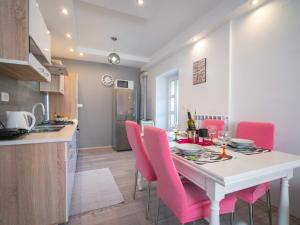 a kitchen and dining room with a table and pink chairs at Apartment Rita by Interhome in Dražice