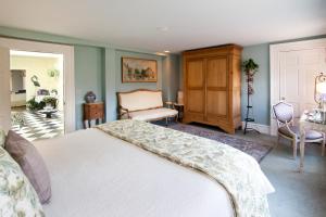 a bedroom with a white bed and a chair at Captain Farris House in South Yarmouth
