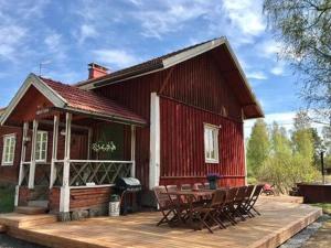 uma casa vermelha com uma mesa e cadeiras num deque em Holiday Home Virtaan väentupa by Interhome em Nuoramoinen