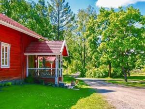 uma casa vermelha com um jardim verde ao lado de uma casa em Holiday Home Virtaan väentupa by Interhome em Nuoramoinen