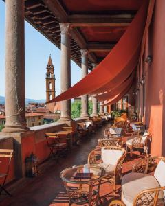 a patio with tables and chairs and a clock tower at Hotel Palazzo Guadagni in Florence