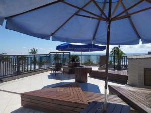 a patio with an umbrella and a table and benches at Hotel Nautico in Guaratuba