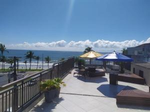 eine Terrasse mit Tischen und Sonnenschirmen und dem Strand in der Unterkunft Hotel Nautico in Guaratuba