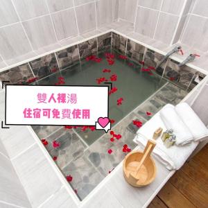 baño con bañera con flores en el suelo en Meizhou Hot Spring Hotel溫泉商旅, en Jiaoxi