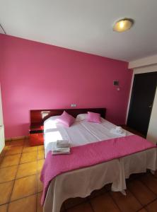 a bedroom with a bed with a pink wall at Hostal San Andrés in Soria