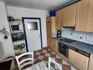una cocina con armarios de madera, mesa y sillas en Gästehaus 24, en Grettstadt