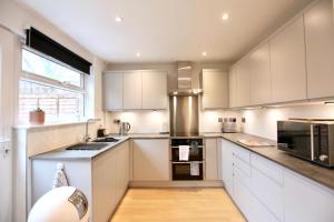 a kitchen with white cabinets and a large window at Stylish Cambridge City Pad in Chesterton
