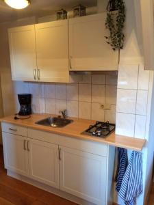 Una cocina con gabinetes blancos y un fregadero. en De Slotruine, en Egmond aan den Hoef