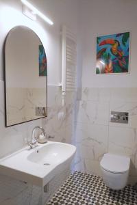 ein Badezimmer mit einem Waschbecken, einem WC und einem Spiegel in der Unterkunft La Jaguara artistic house in the center of Gdansk in Danzig