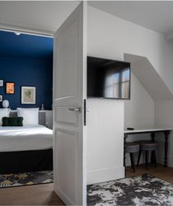 a bedroom with a bed and a sliding door with a bed and a desk at Le Belleval in Paris