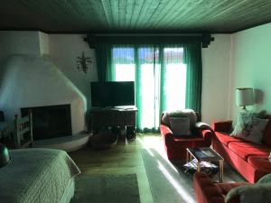 uma sala de estar com um sofá vermelho e uma televisão em TOP LOCATION - Klosters center - 130m distance to ski lift Parsenn Gotschnabahn and railway station Klosters Platz - direct connection to Davos em Klosters