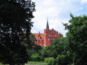 a red building with a steeple in the middle of trees at Ristinge Ferielejligheder in Humble