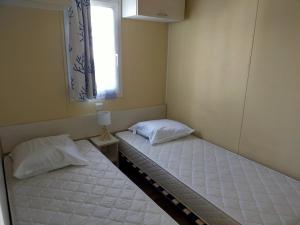 2 camas individuais num quarto com uma janela em Camping Cap Soleil île d'Oléron 4 étoiles em La Bétaudière