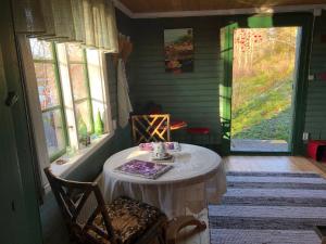 een kleine kamer met een tafel, stoelen en ramen bij Fisherman s Cottage overlooking the river in Avesta