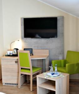 a living room with a desk and a green chair at Hotel Restaurant Bürgerklause Tapken in Garrel
