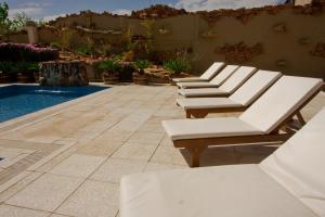 a row of white lounge chairs next to a pool at Hotel Tower Inn & Suites in San Rafael