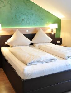 a large bed with white sheets and pillows at Hotel Restaurant Bürgerklause Tapken in Garrel