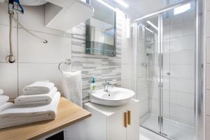 a white bathroom with a sink and a shower at Apartments Tivoli in Ljubljana