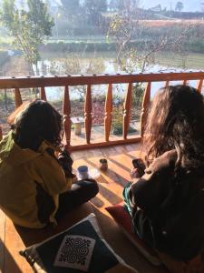 two girls sitting on a porch looking out at a river at Dồn Dao Homestay in Ha Giang +108 photos