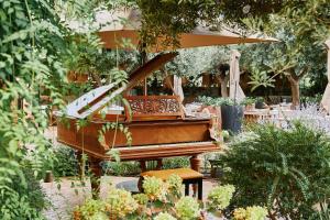 a piano in a garden with a table and chairs at Faustino Gran Relais & Chateaux in Ciutadella