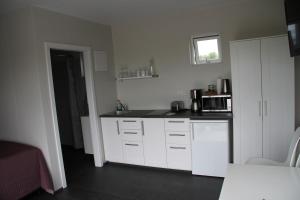 a kitchen with white cabinets and a black counter top at Strýta Apartment 2 in Ölfus