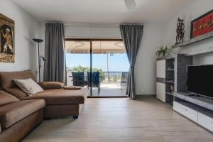 un salon avec un canapé et une télévision dans l'établissement Apartamento Acantilados, à Acantilado de los Gigantes