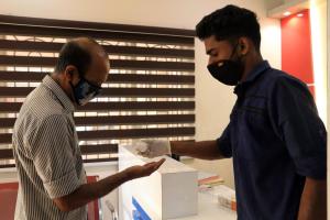 Dwóch mężczyzn w maskach patrzy na pudełko. w obiekcie East Coast w mieście Thiruvananthapuram