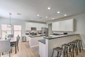 a kitchen with white cabinets and a bar with bar stools at Game Room and Pool Spacious Queen Creek Home! in Queen Creek
