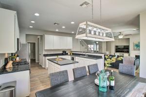 a kitchen and living room with a dining table and a kitchen with white cabinets at Game Room and Pool Spacious Queen Creek Home! in Queen Creek