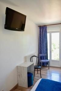 Pokój z telewizorem na ścianie ze stołem i krzesłem w obiekcie Domaine de Lacave w mieście Lacave