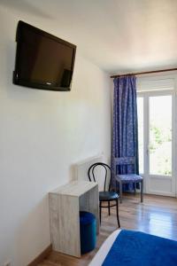 a room with a tv on the wall with a table and a chair at Domaine de Lacave in Lacave