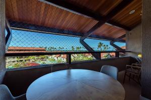 a wooden table in a room with two large windows at Oka Beach Resort #404G - Conforto por Carpediem in Porto De Galinhas