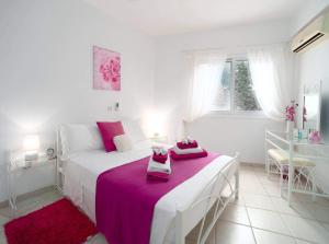 a white bedroom with a bed with pink sheets at Tala Hills Sea view apartment in Paphos City