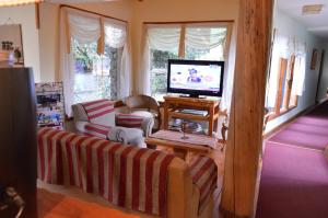 ein Wohnzimmer mit einem Sofa und einem TV in der Unterkunft Hostería Traunco in Villa La Angostura