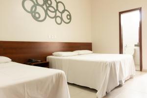 2 bedden met witte lakens in een kamer bij Contagem Centro Hotel in Contagem