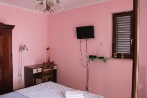 1 dormitorio con paredes rosas, 1 cama y escritorio en Summer house in Novalja, en Novalja