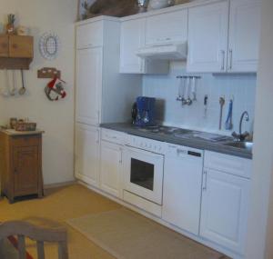 a kitchen with white cabinets and a stove top oven at Komfort-Fewo Sylvia in Spiegelau