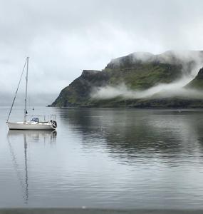 a sailboat in a body of water with a mountain at Old Captain Guest House in Portree