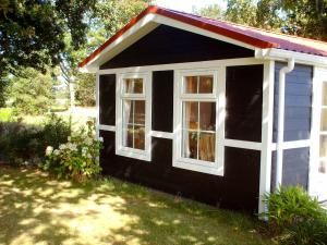 Cette petite maison en noir et blanc possède 2 fenêtres. dans l'établissement Holiday Home De Wierde by Interhome, à Den Oever