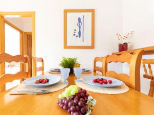 a wooden table with plates of fruit on it at Apartment Roquemar by Interhome in L'Ampolla