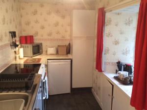 a small kitchen with a sink and a microwave at Holiday Home Craigton Cottage by Interhome in Dunkeld