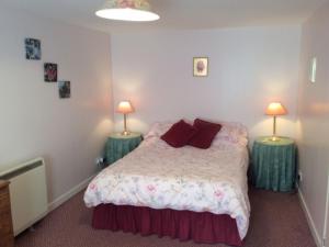 a bedroom with a bed with two lamps on two tables at Holiday Home Craigton Cottage by Interhome in Dunkeld