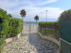 a gate leading to the beach with palm trees at Apartment Le Cormoran by Interhome in Saint-Laurent-du-Var