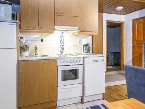 - une cuisine avec des appareils blancs et des armoires en bois dans l'établissement Holiday Home Alppitalo sinitähti 9 apt 2 by Interhome, à Tahkovuori