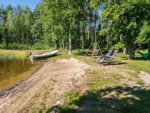 un barco y dos sillas a orillas de un río en Holiday Home Telkänkolo by Interhome, en Pertunmaa