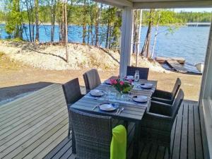 una mesa de comedor en un porche con vistas al agua en Holiday Home Hot pool cottage laurinranta by Interhome en Ihamaniemi